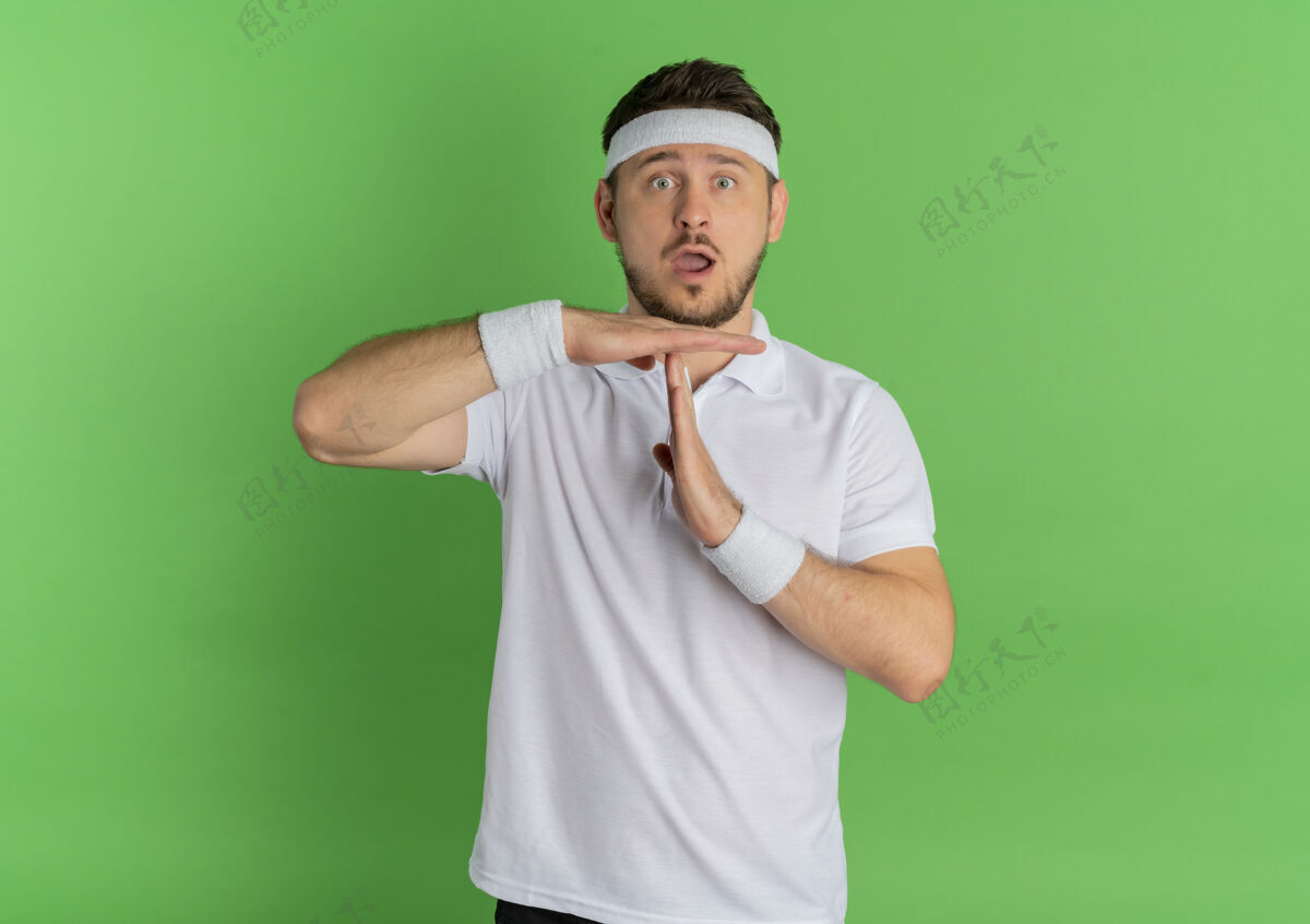 手势身穿白衬衫 头戴头巾的年轻健身男子站在绿色的墙壁上 做出暂停的手势教练健身男性