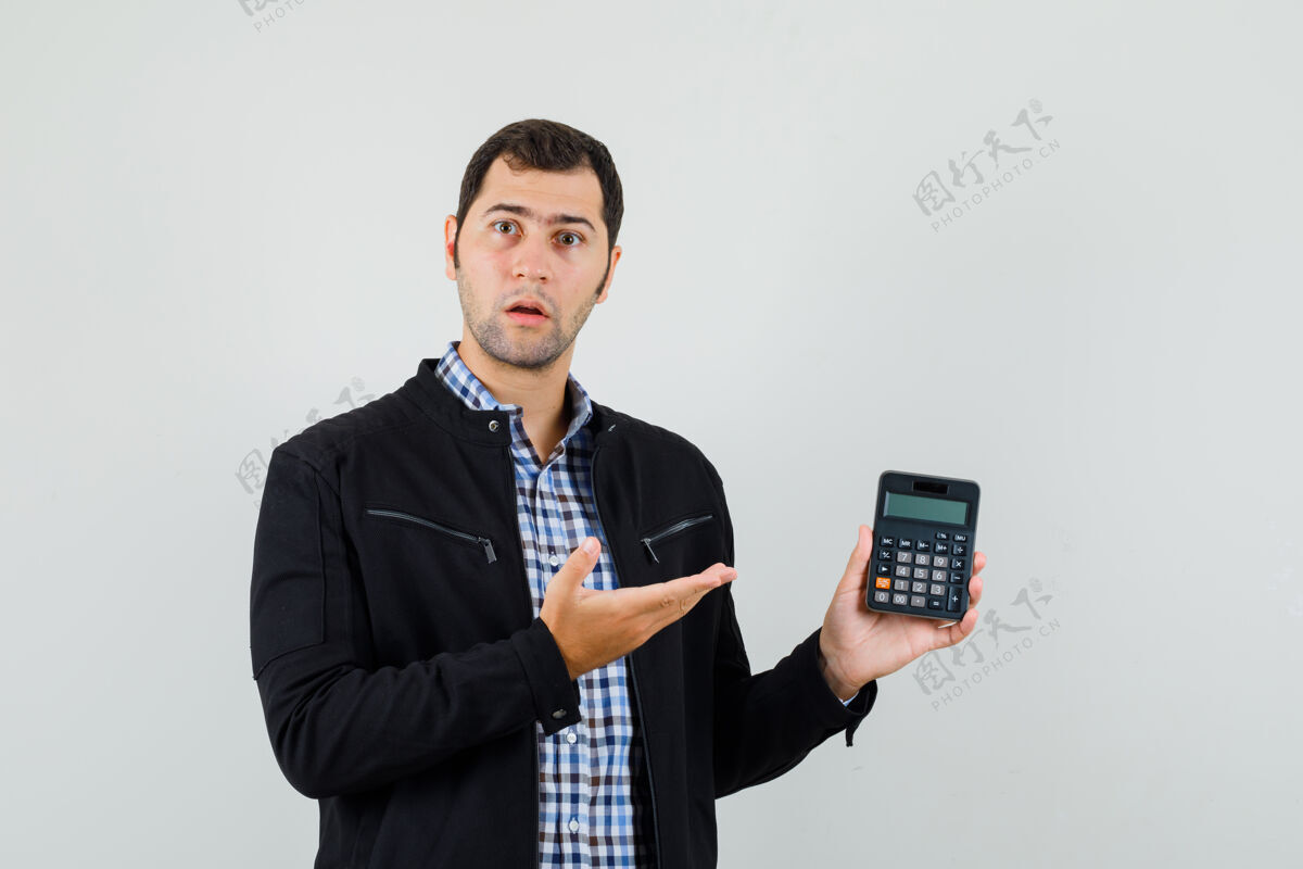朋友年轻人穿着衬衫 夹克衫 面带疑惑地展示计算器 正面视图脸交叉成人