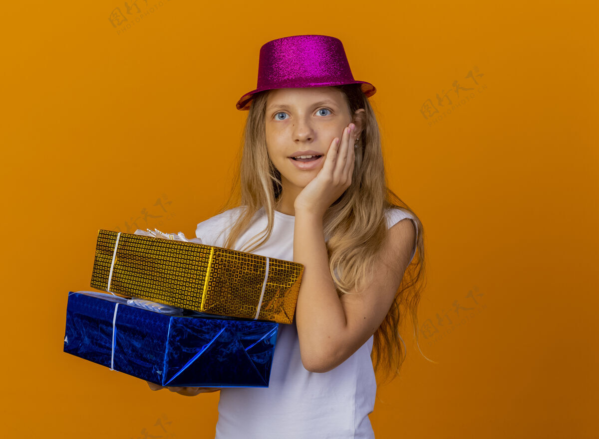 拿着戴着节日帽子拿着礼品盒的漂亮小女孩帽子漂亮快乐