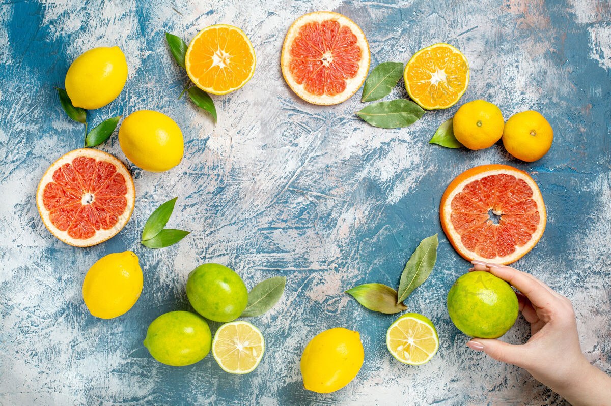 柑橘顶视图圆形排柑橘类水果柠檬切葡萄柚柑橘柠檬在女人手上放在蓝白色的桌子上柑橘类水果圈食物