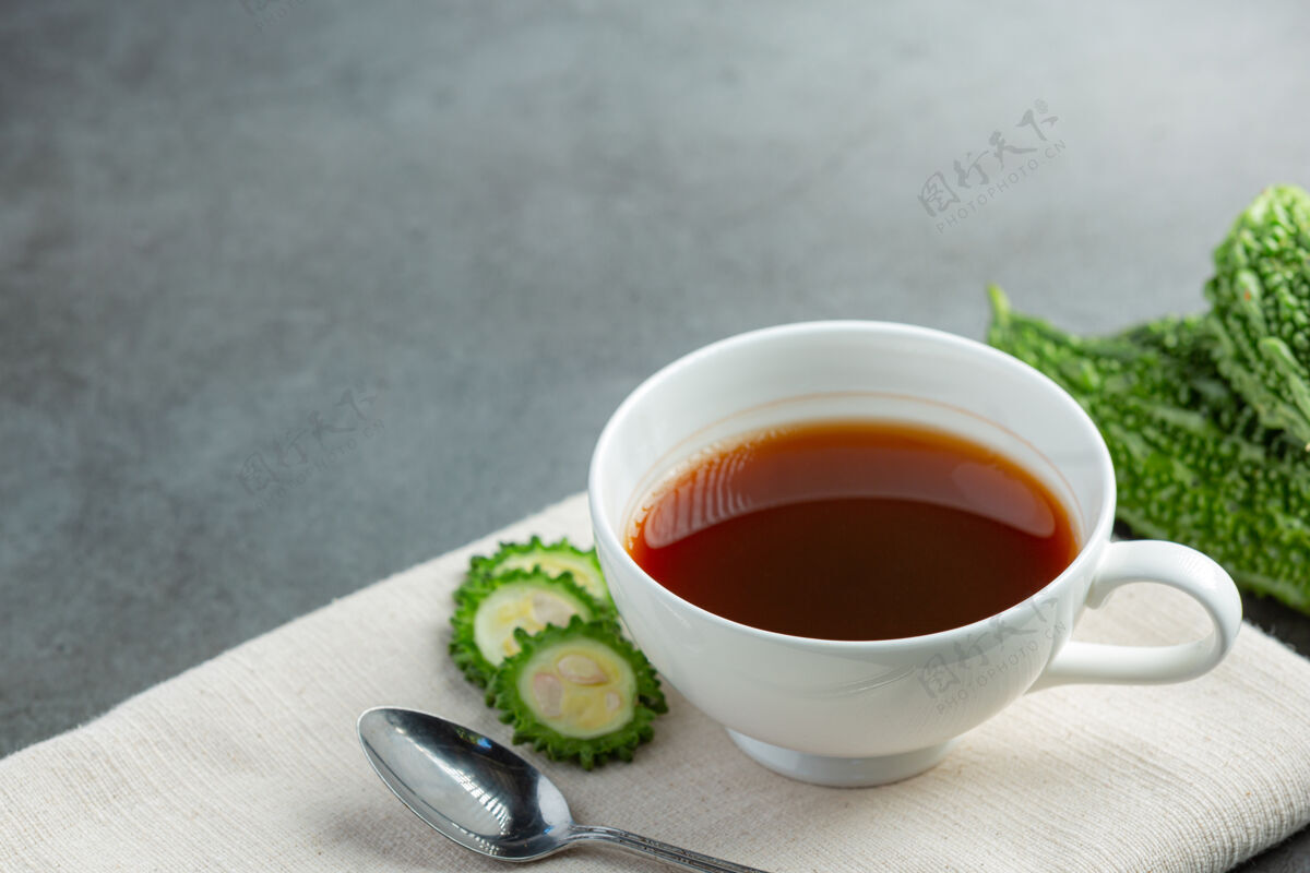 水一杯热的苦瓜茶 将生的苦瓜片放在白织物上蔬菜有益抗氧化剂