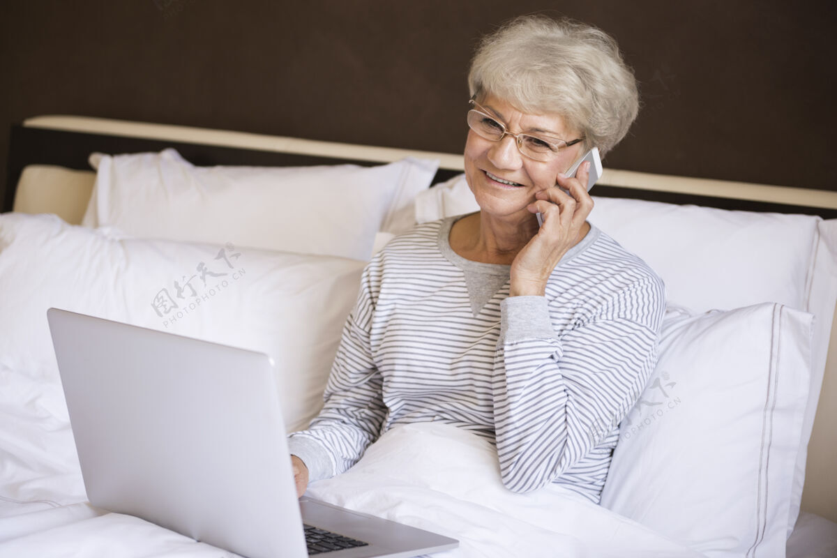 女性忙着在床上工作的老太太讨论日常眼镜