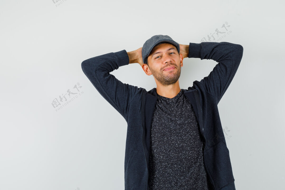 男人穿着t恤 夹克 帽子的年轻人手把手放在脑后 看上去很放松正视图发型胡须肖像