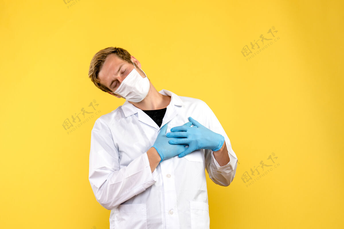 医生正面图黄色背景上的男医生抚摸着他的心脏健康大流行柯维德-医生冠状病毒制服医学
