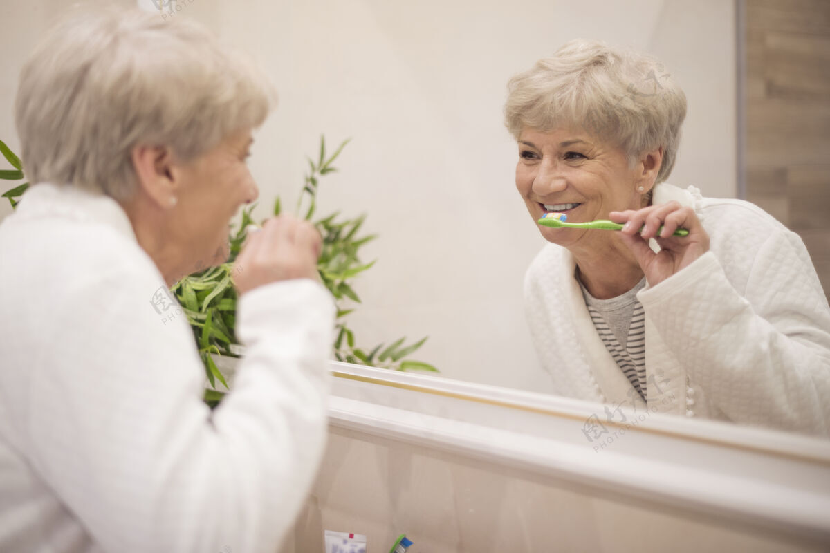 牙科健康对着镜子刷牙手微笑浴室