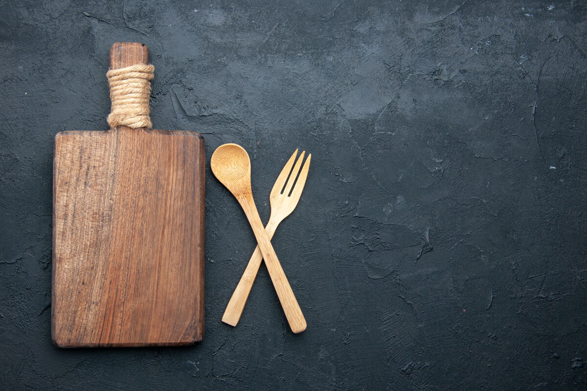 工具顶视图交叉木汤匙和叉子服务板在黑暗的桌子上与副本的地方餐具厨房十字架