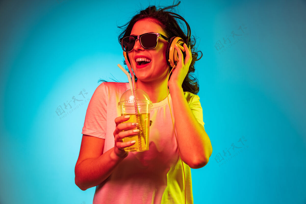 迪斯科舞厅快乐的年轻女子戴着耳机在时髦的蓝色霓虹灯工作室里跳舞和微笑人类霓虹灯表情
