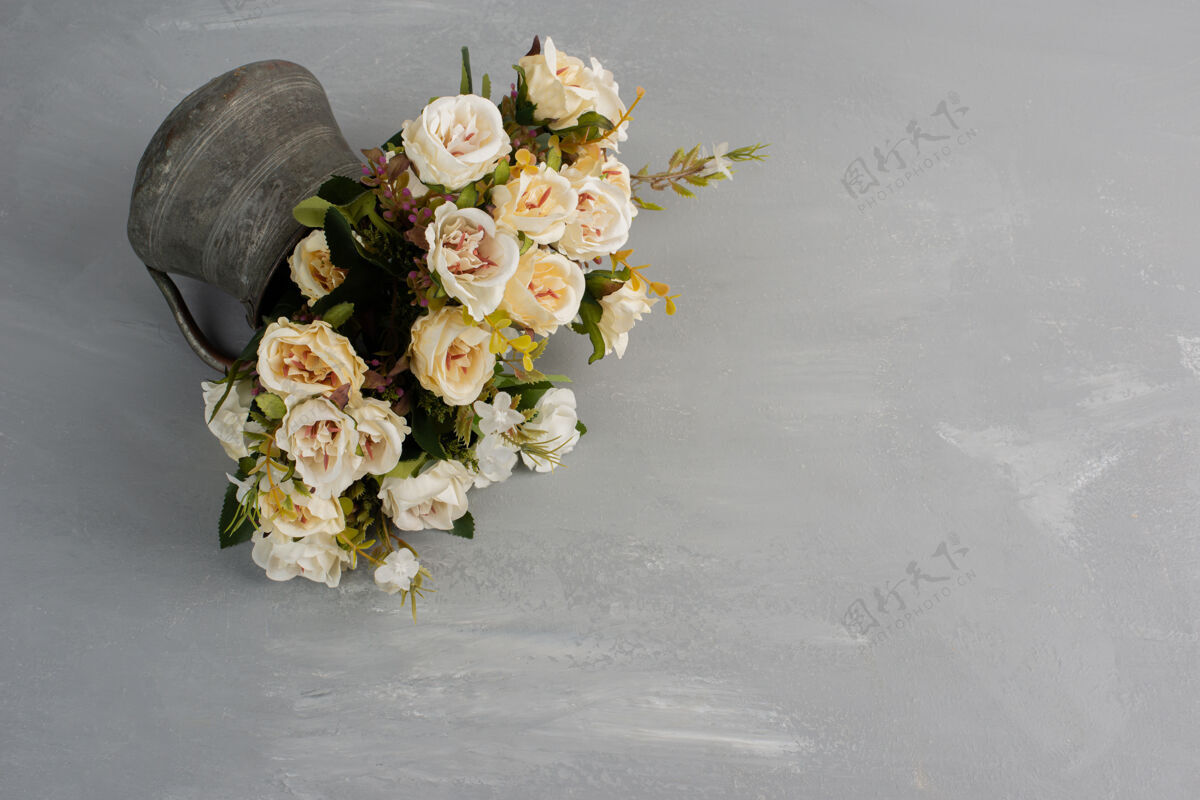 叶美丽的白玫瑰花束在灰色的表面玫瑰安排开花