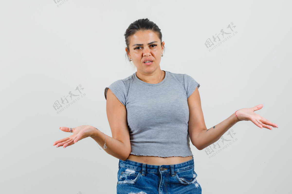 女年轻的女性穿着t恤 短裤 两手摊开 看起来很困惑短裤专业蔓延