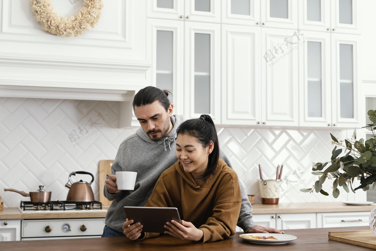 科技一对夫妇在厨房吃早餐 并使用平板电脑休闲一起室内