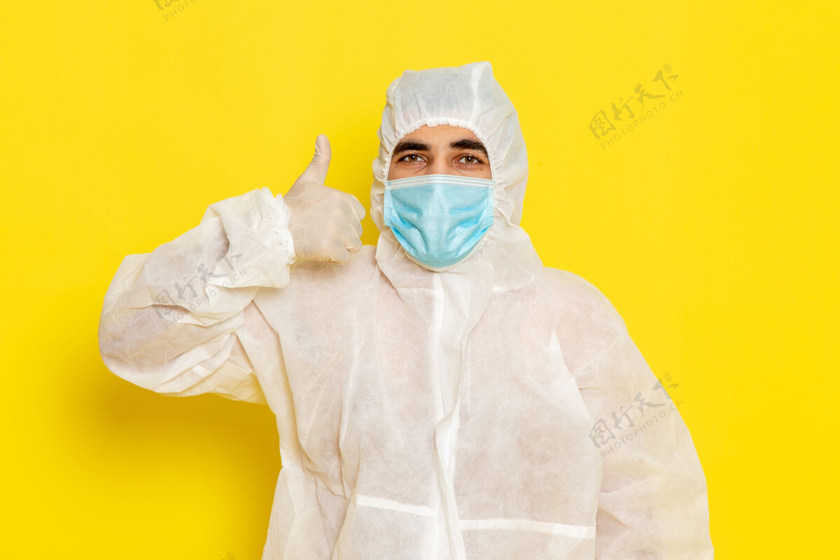 科学黄色办公桌上穿着白色特殊防护服带面罩的男科学工作者正面图科学工作者科学化学颜色危险防护套装医生