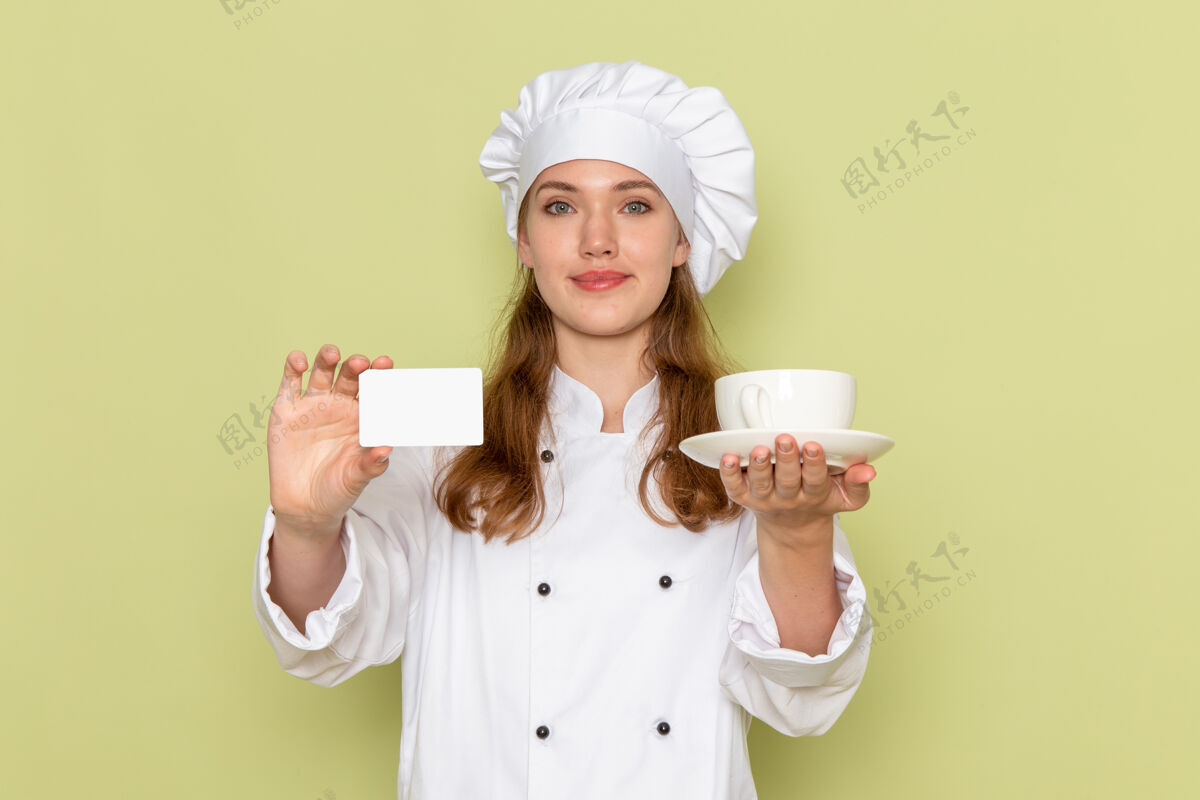 淋浴身着白色厨师服的女厨师正拿着杯子和卡片站在绿色的墙上女厨师前面厨房