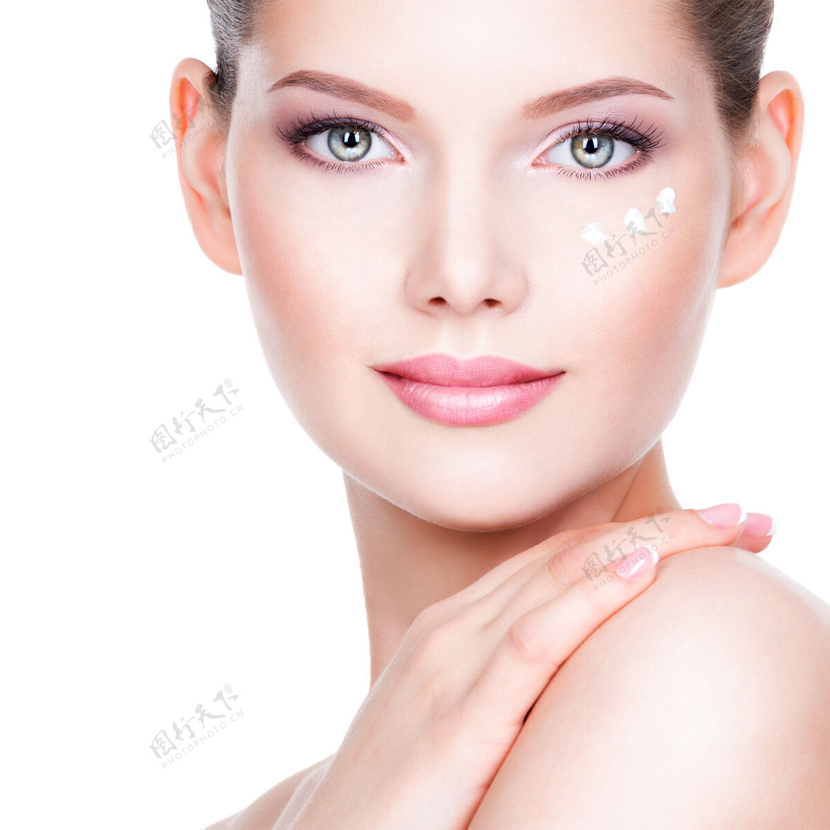 模特年轻女子在她美丽的脸上涂面霜的特写照片-在白墙上皮肤护理治疗化妆品