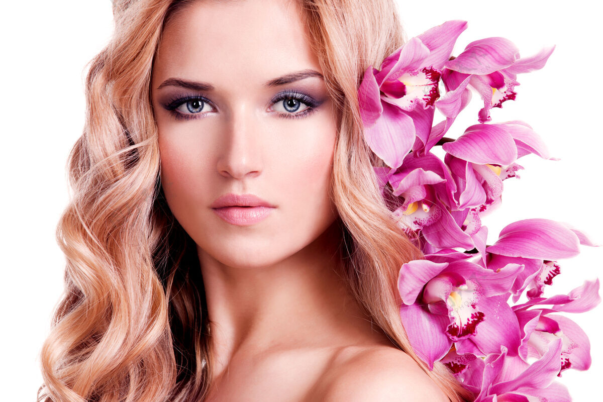 特写美丽的女人的脸 健康的皮肤和粉红色的花在白色的墙上模特年轻自然