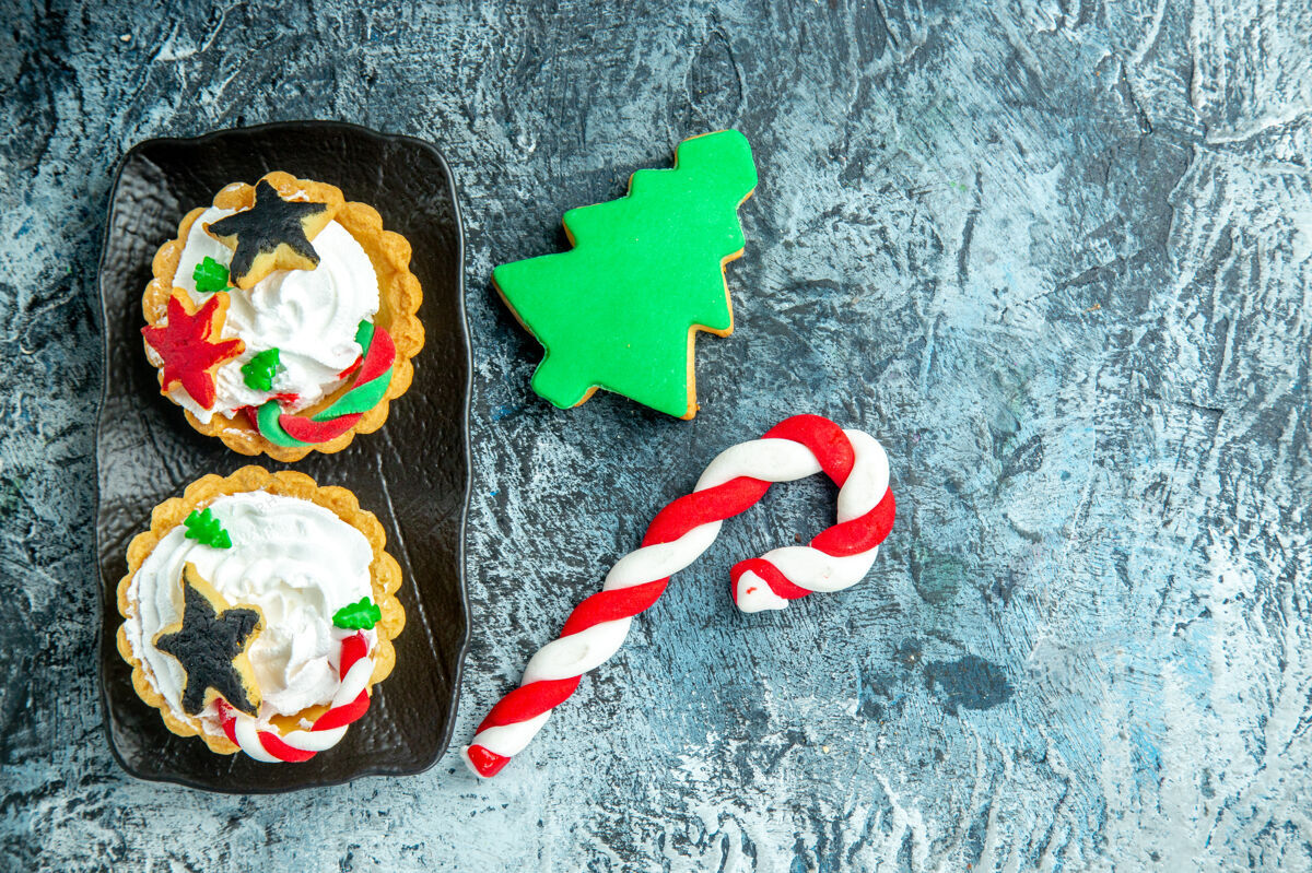 盘子上图：黑色盘子上的圣诞馅饼 灰色桌子上的圣诞糖果和圣诞树饼干糖果圣诞树饼干
