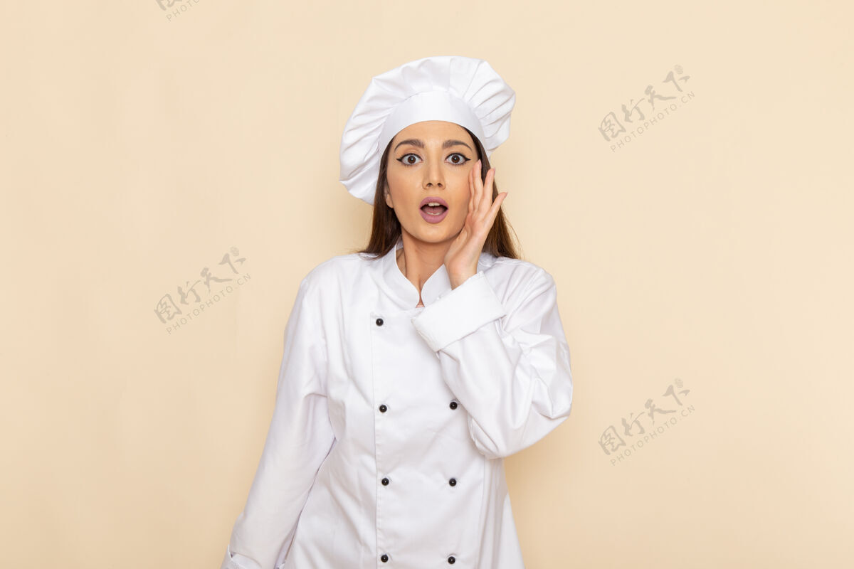 烹饪身穿白色厨师服的年轻女厨师在浅白的墙上摆出惊讶的表情女性帽子厨房