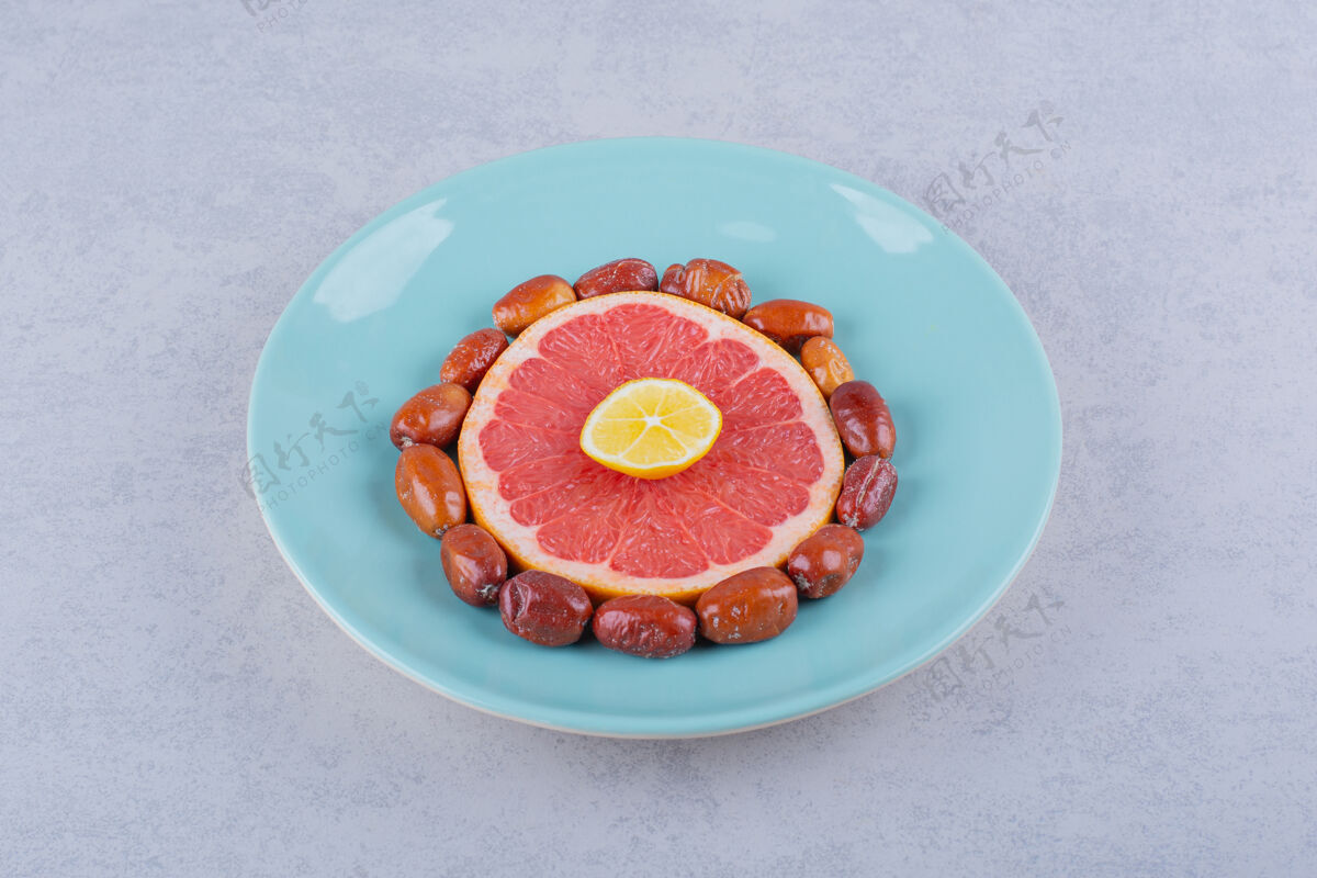 葡萄柚把成熟的葡萄柚 柠檬和银莓片放在蓝色盘子里柑橘切块切片