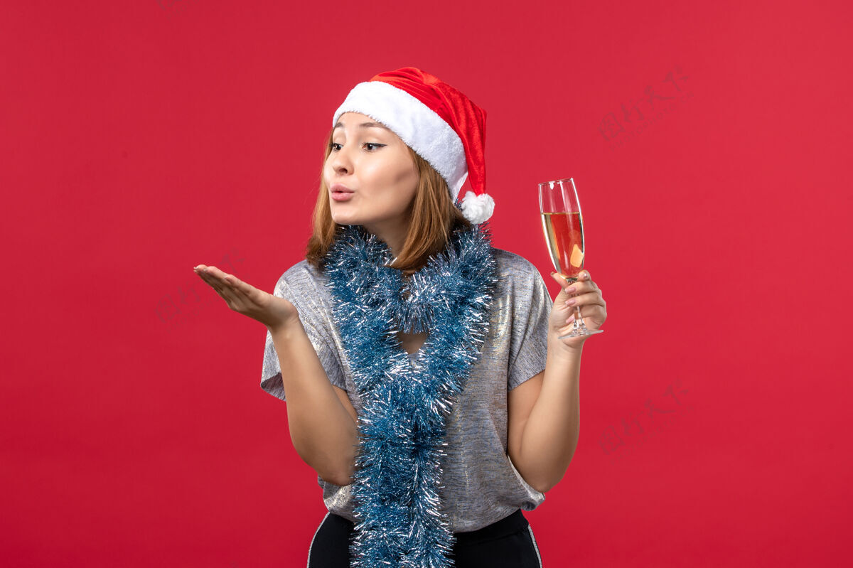 肖像正面图：年轻女性在红墙派对上送飞吻圣诞视图成人发送