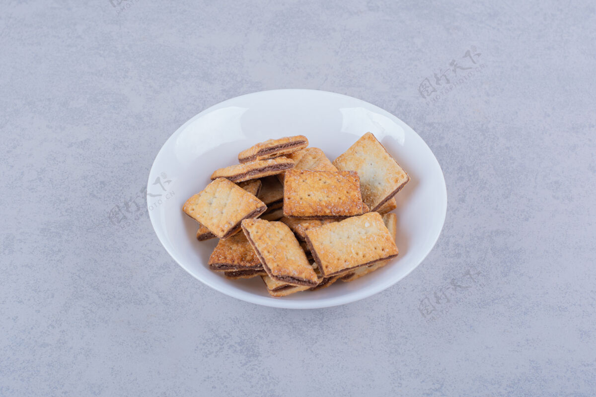 谷类食品石头桌上放着一盘白色的脆饼干饼干食物烘焙