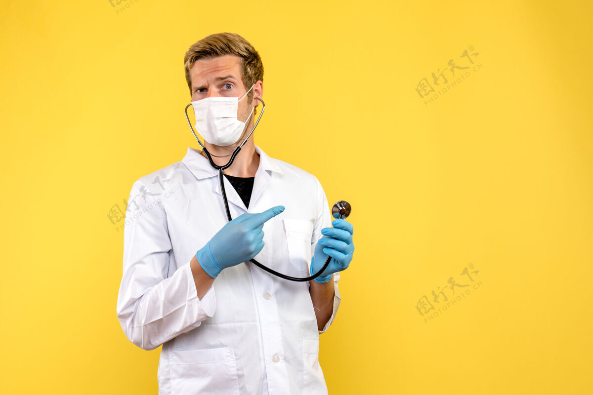 医生正面图男医生在无菌口罩上黄色背景大流行病毒共价健康视图大流行听诊器