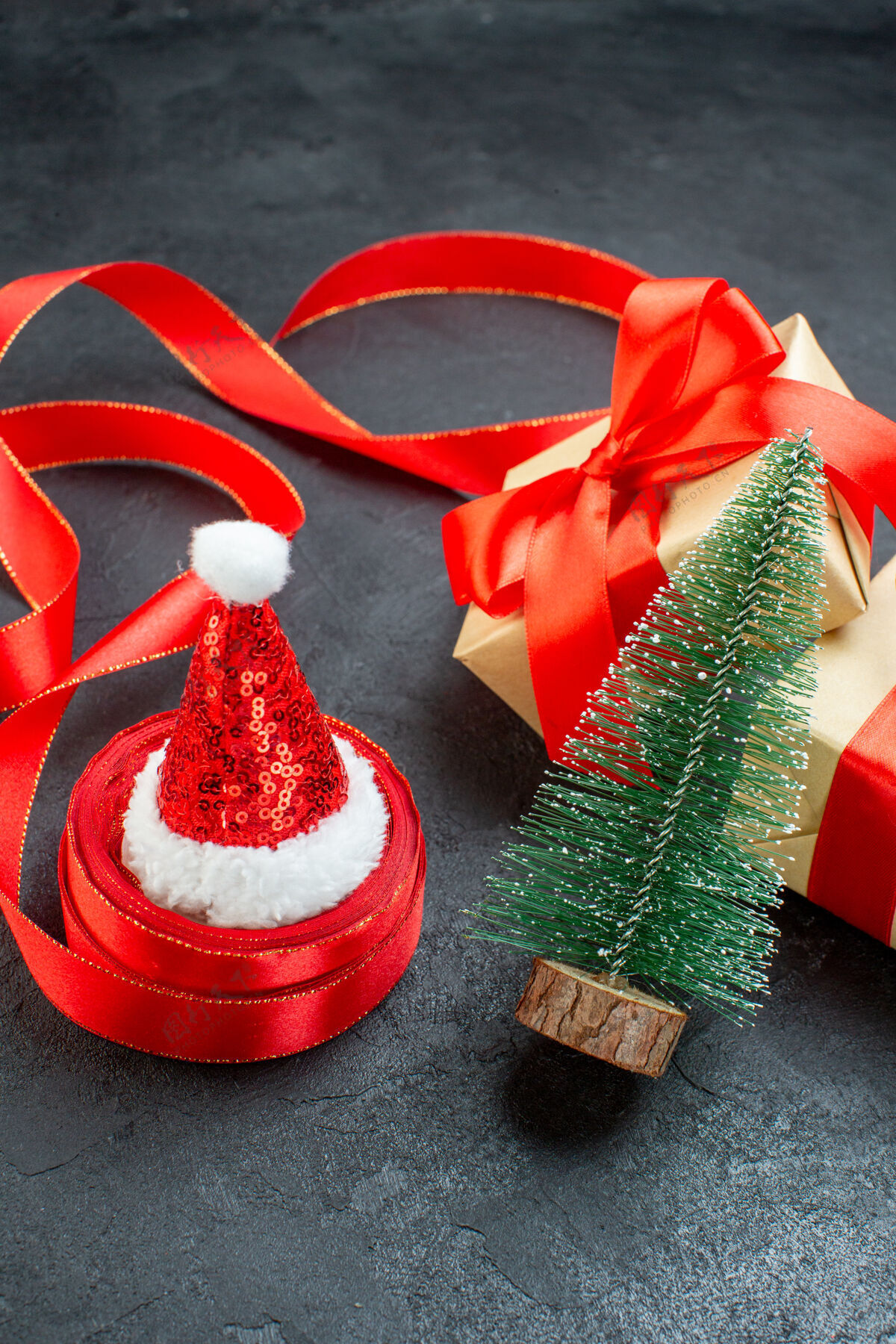 花前视图美丽的礼物与红丝带和圣诞树圣诞老人帽子在一个黑暗的桌子上轮子帽子视图