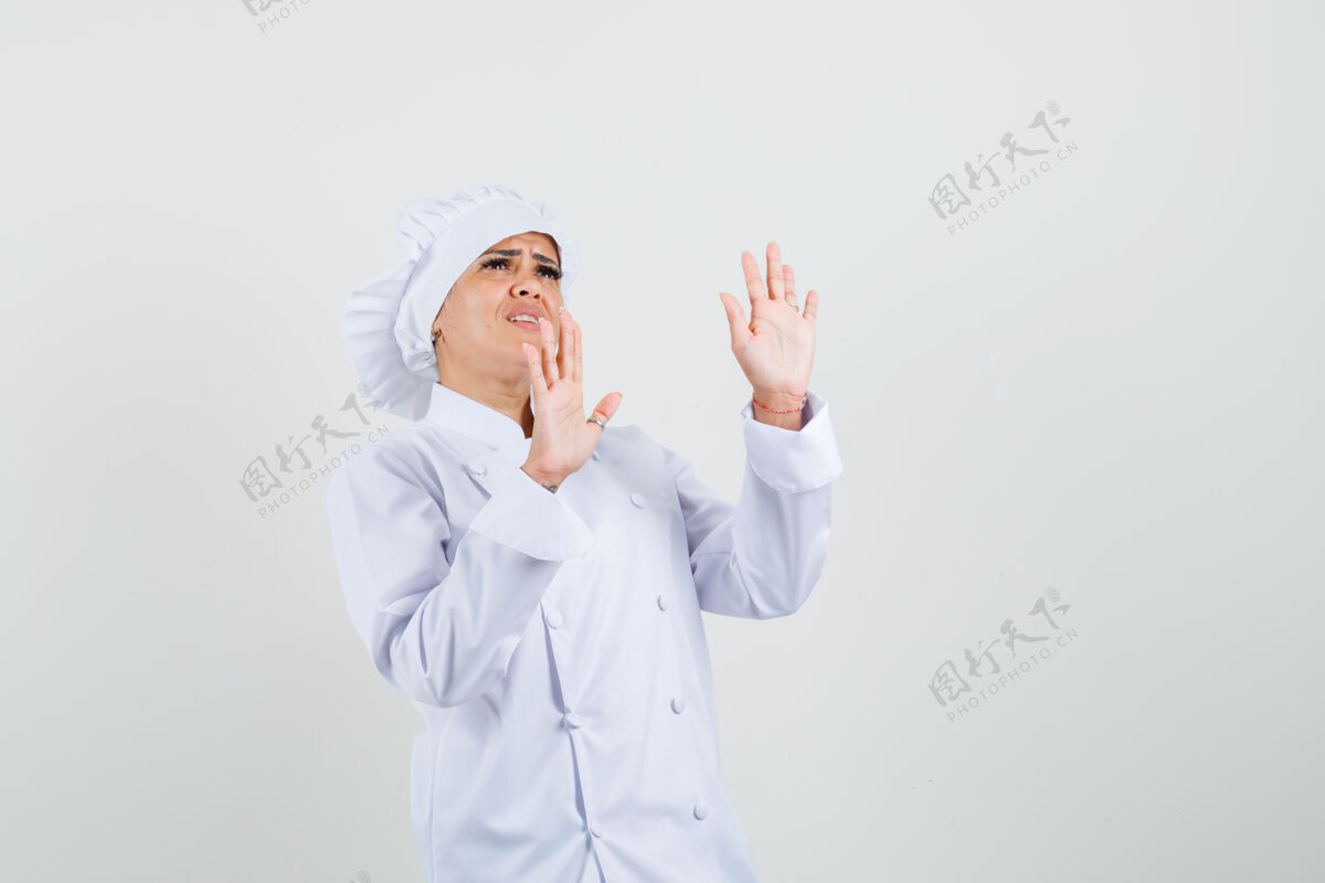 工作穿着白色制服的女厨师举手自卫 看上去很害怕工业专业服务