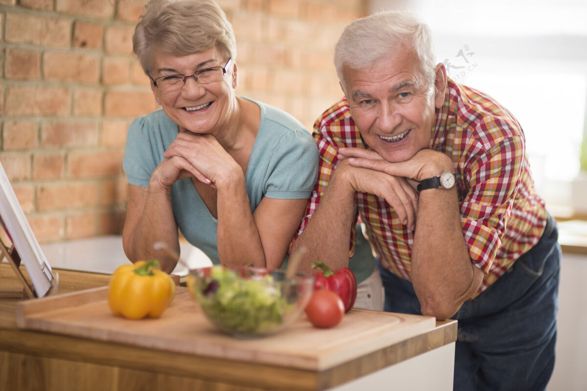 活力家庭厨房里快乐老人的画像享受晚餐季节