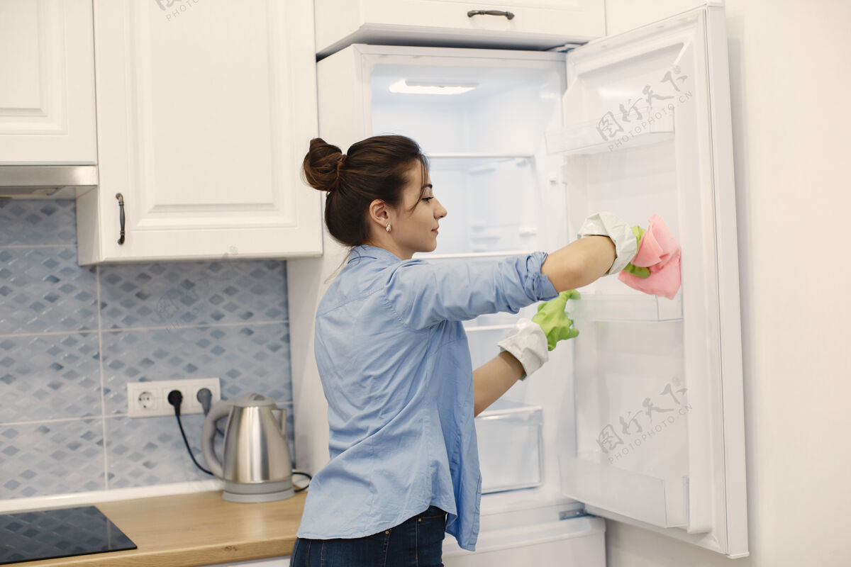 清洁在家工作的家庭主妇穿蓝色衬衫的女士家喷雾清洁