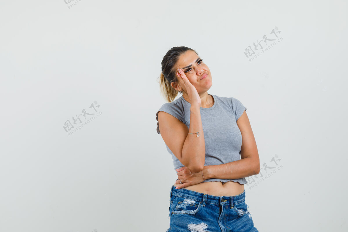 人性化年轻的女士穿着t恤 短裤站在思考的姿势里 看上去犹豫不决兴奋短裤友谊