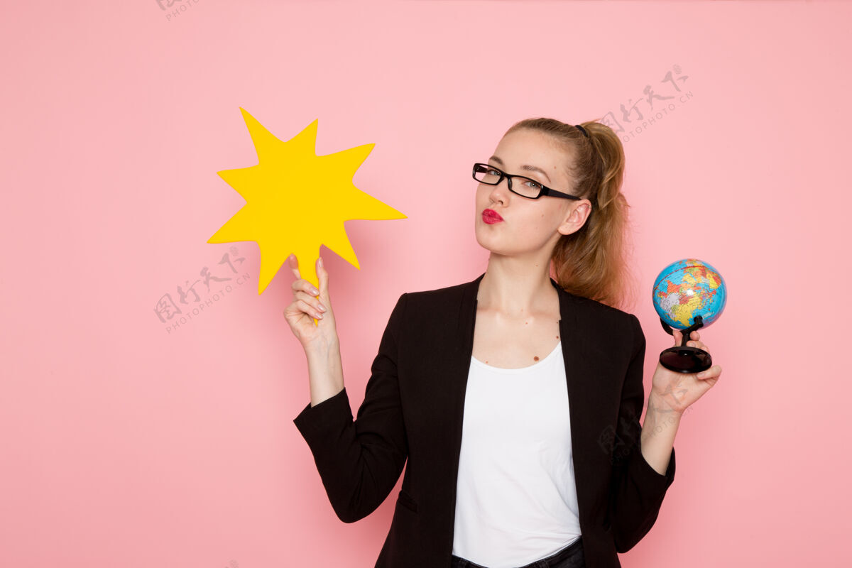 工人身穿黑色夹克的女上班族的正面图 粉色墙上举着一个带地球仪的黄色大牌子业务肖像办公室