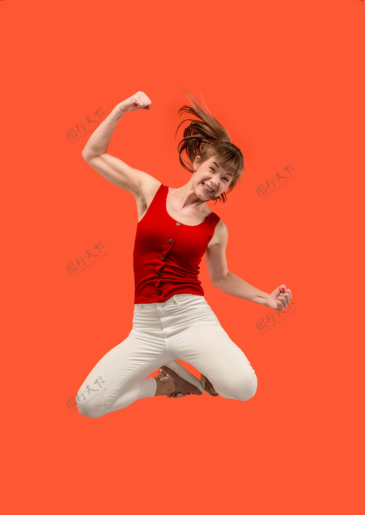 胜利在移动的自由相当快乐的年轻女子跳跃和对橙色的手势半空中拍摄舞蹈活动时尚