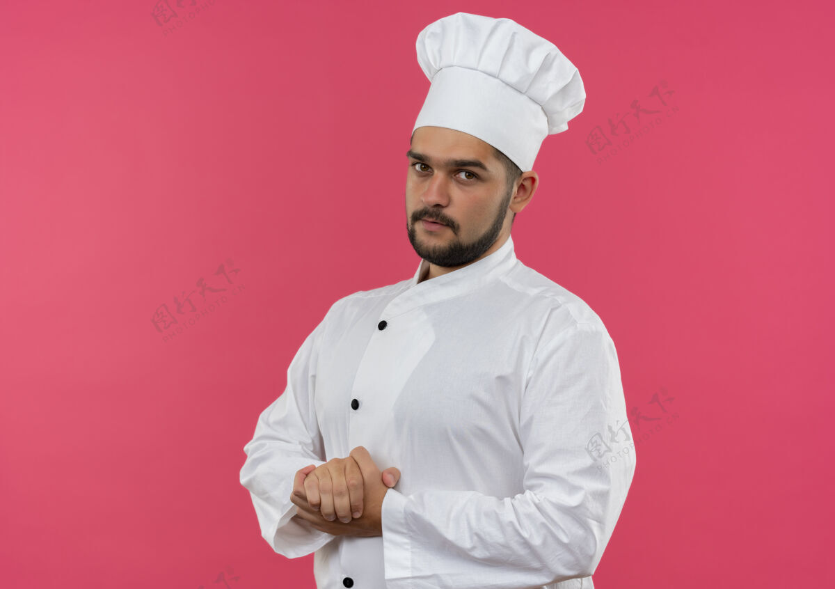 烹饪穿着厨师制服的年轻男厨师手放在一起 看起来在粉红色的空间里与世隔绝厨师年轻粉红