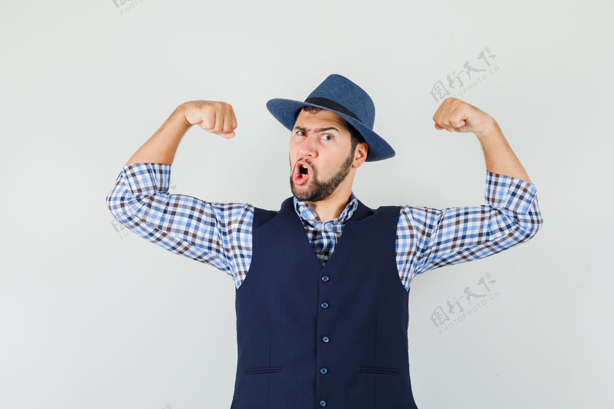 展示穿着衬衫 背心 帽子 展示手臂肌肉的年轻人 看上去很有力量帽子手臂休闲