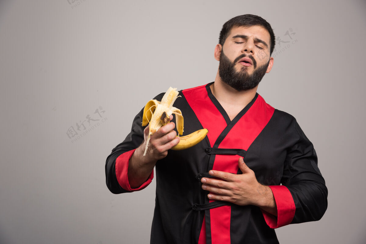 模型年轻人在灰色的墙上吃香蕉人男水果