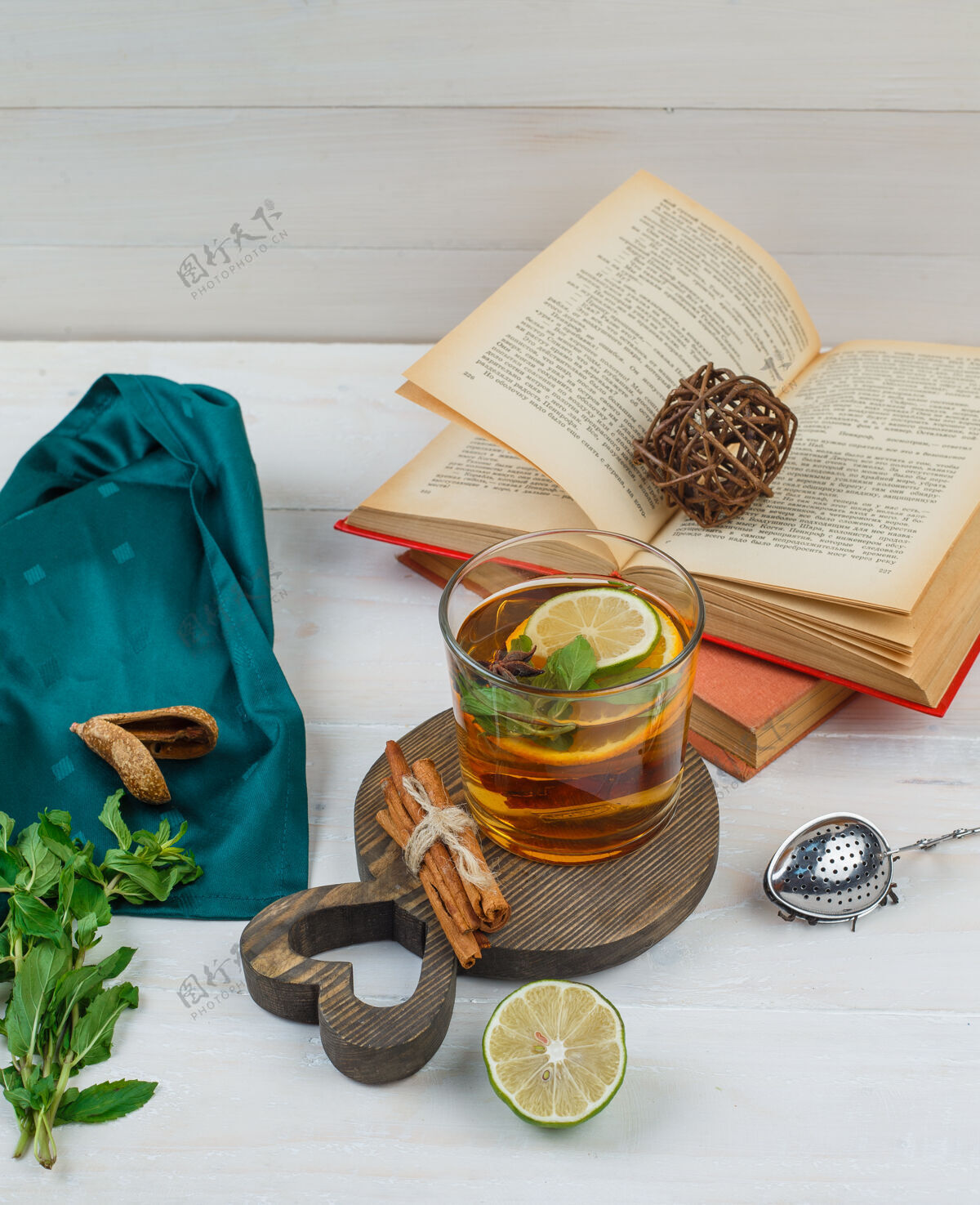 新鲜一些凉茶和肉桂与书籍 柠檬 香料和绿领巾在木板上芳香热植物