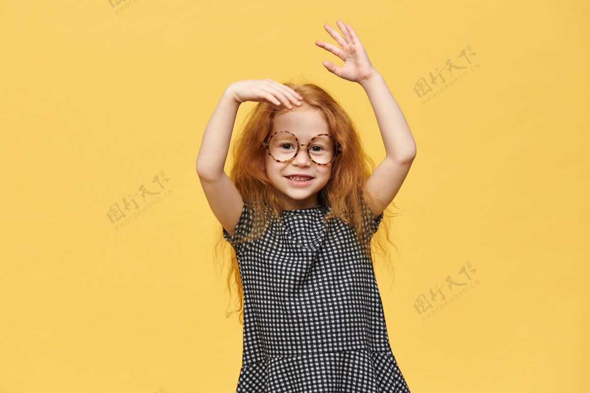 童年迷人的红发高加索女婴 穿着连衣裙 戴着圆眼镜 情绪激动地打着手势 喜闻乐见 面带微笑孩子女人可爱