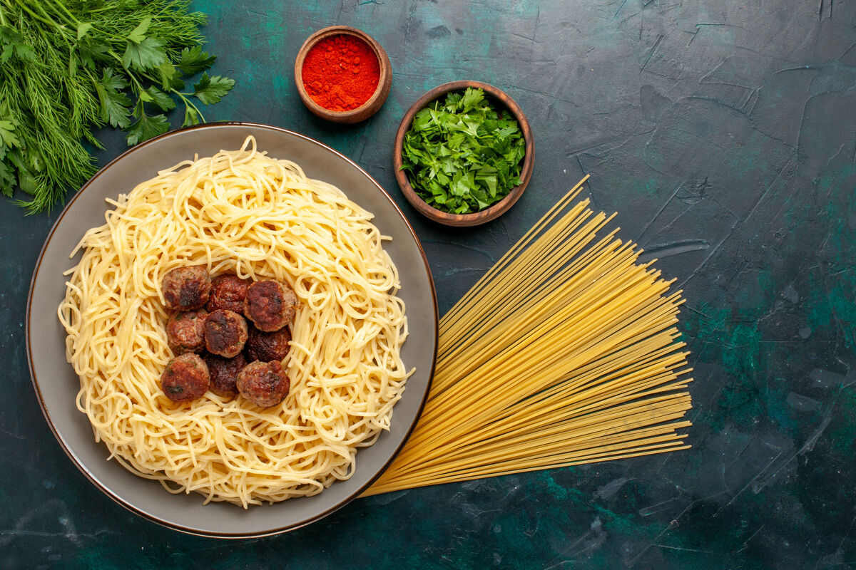 烹饪俯视图煮熟的意大利面食 深蓝色表面有肉丸和绿色菜肴面团绿色