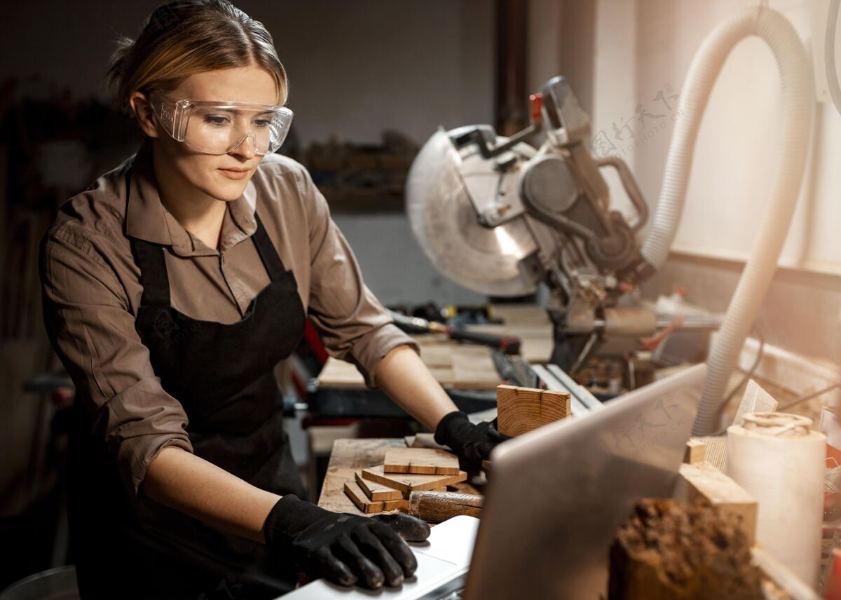 工作女木匠戴着安全眼镜用笔记本电脑女性资格职业