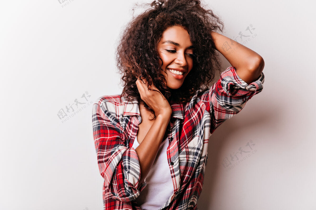 欢快轻松的卷发女孩摆出快乐的微笑穿着考究的非洲年轻女子的肖像时尚女士模特