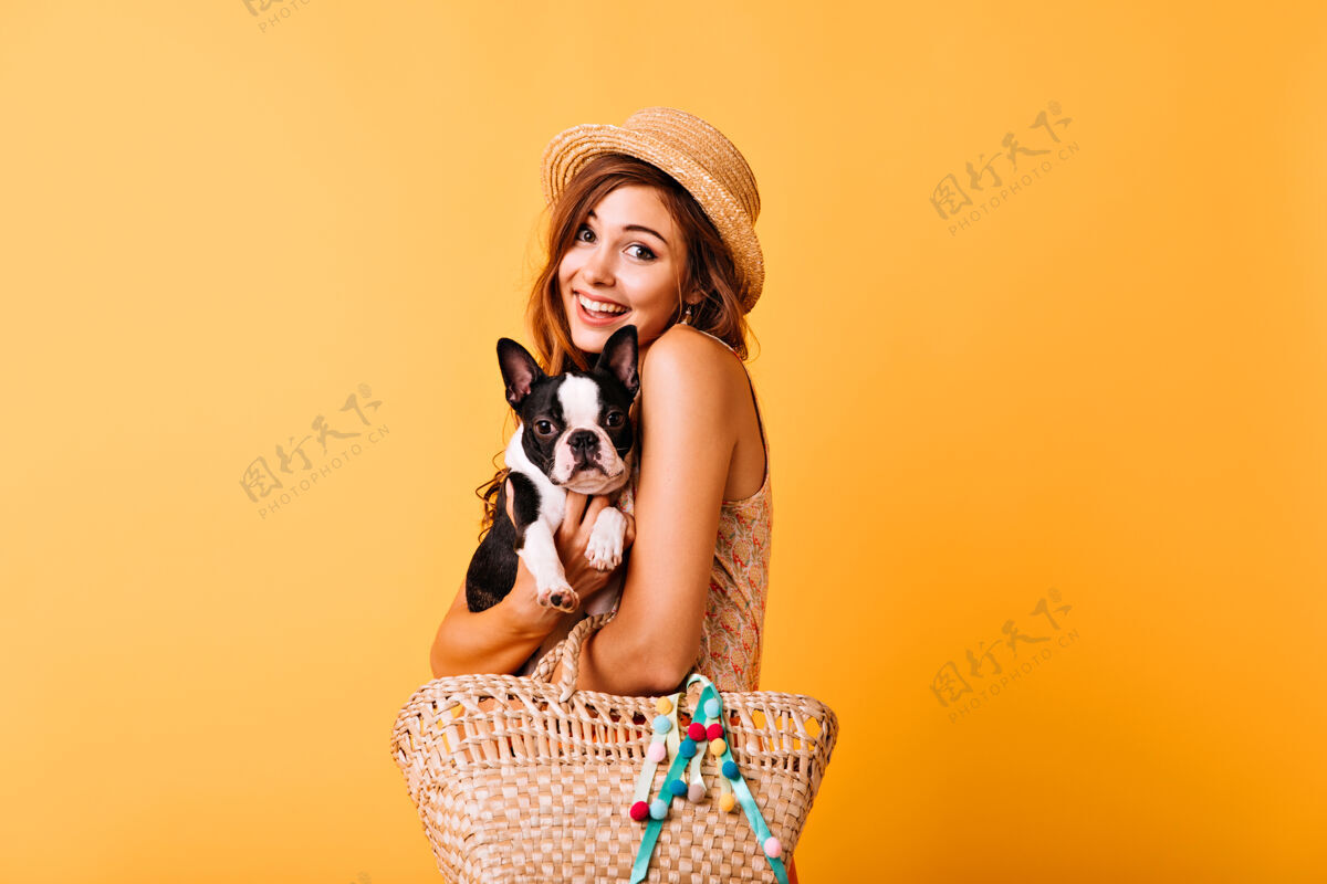 黄色轻松的白种女人抱着她的可爱的狗兴奋的红发女孩戴着草帽抱着法国斗牛犬女性女人斗牛犬