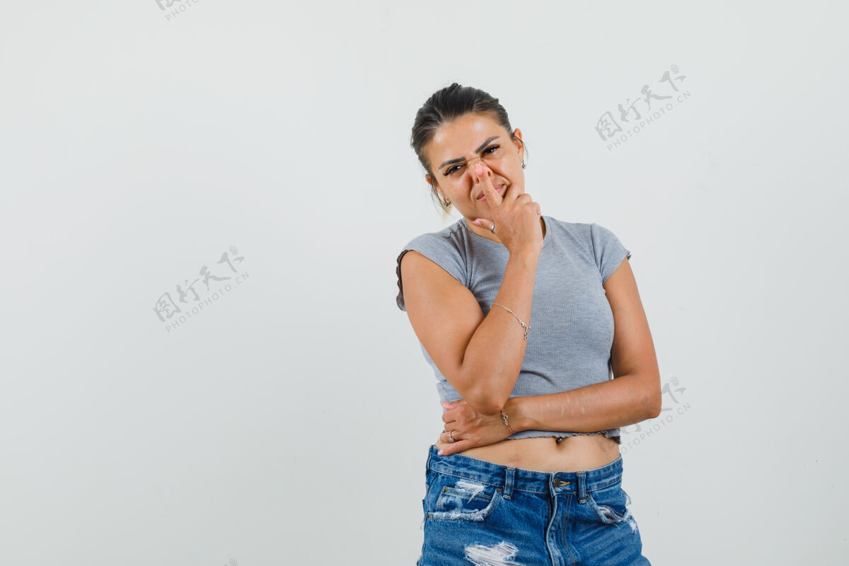 女性穿t恤 短裤的年轻女士用手指触摸鼻子T恤鼻子手指