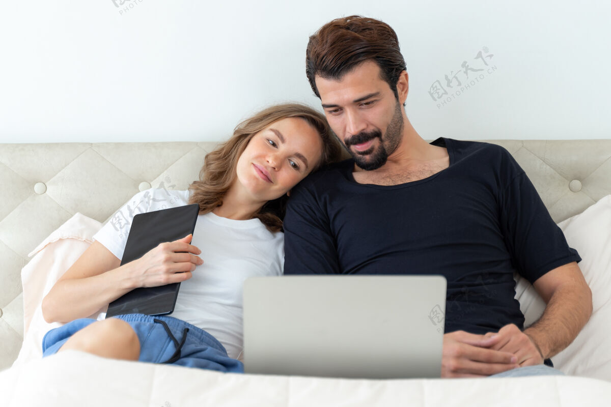 男朋友英俊的丈夫和美丽的妻子在卧室里用笔记本电脑看电影 感觉很浪漫球员赢家妻子