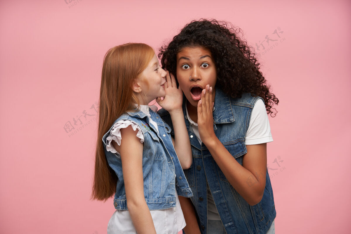 长室内写真的年轻女孩穿着家庭装 在粉红色的衣服上摆姿势 双手贴在脸上 互相分享令人惊讶的消息深色休闲告诉