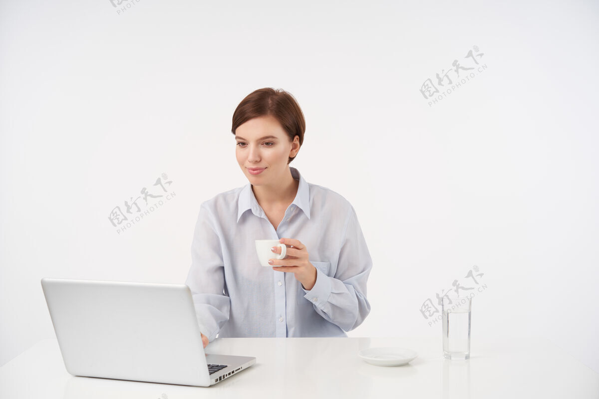 水室内肖像 漂亮的棕色头发的年轻女子 随意的发型 一边喝着咖啡 一边用现代的笔记本电脑和白色的工作 积极的微笑优雅黑发玻璃