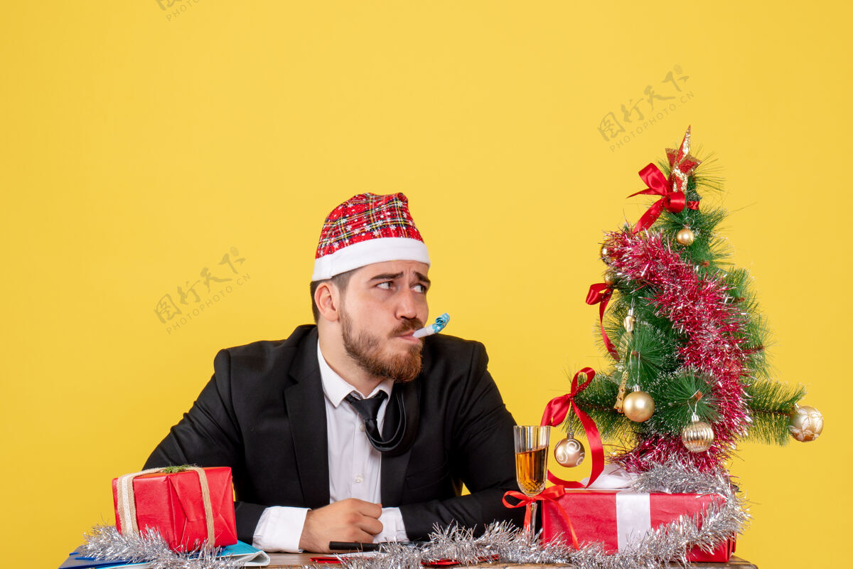 商人正面图：坐在桌子后面的男工人拿着黄色的礼物行政人员圣诞节工人