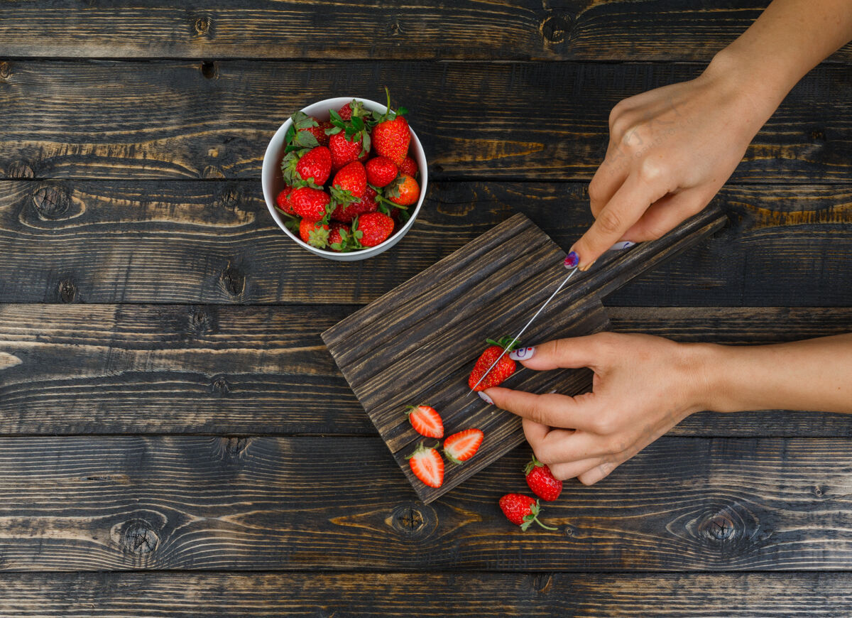 草莓手用刀在木板上切草莓切碎木头甜
