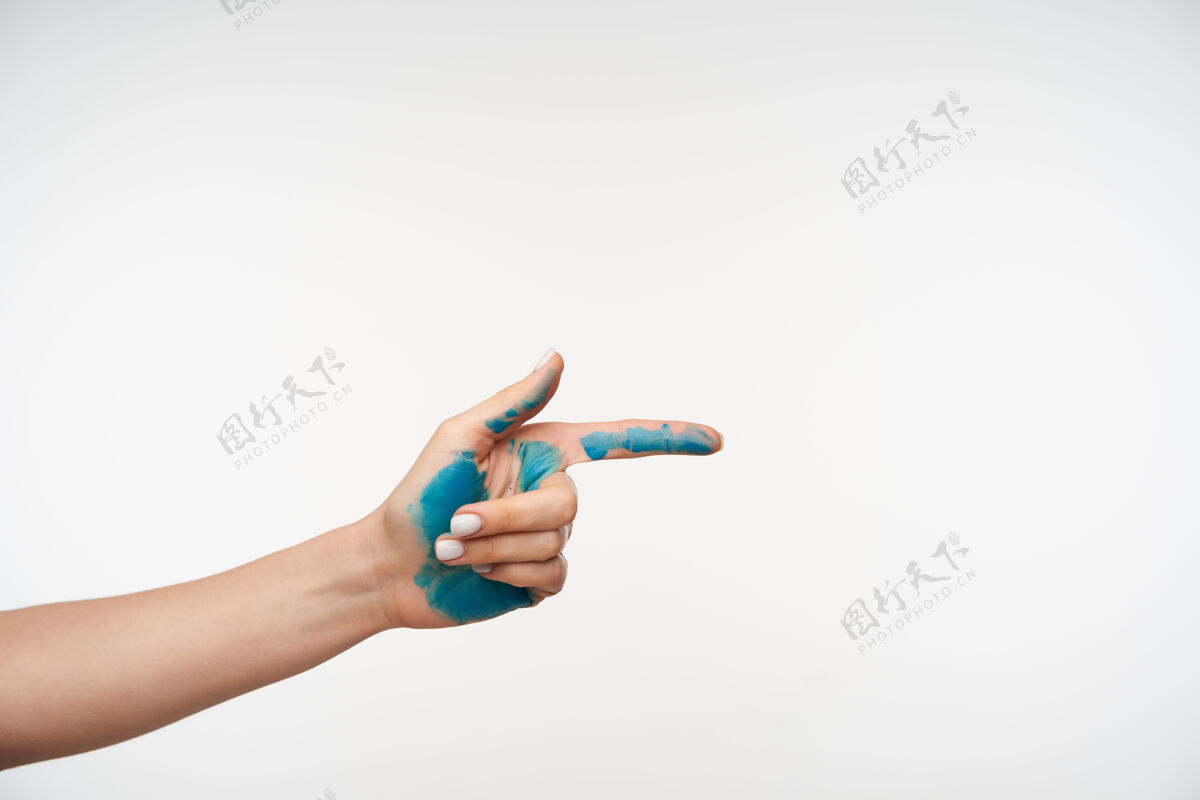 染色女士手上涂有蓝色颜料的剪短肖像被举起 同时用食指指向前方 被隔离在白色上身体站立女士
