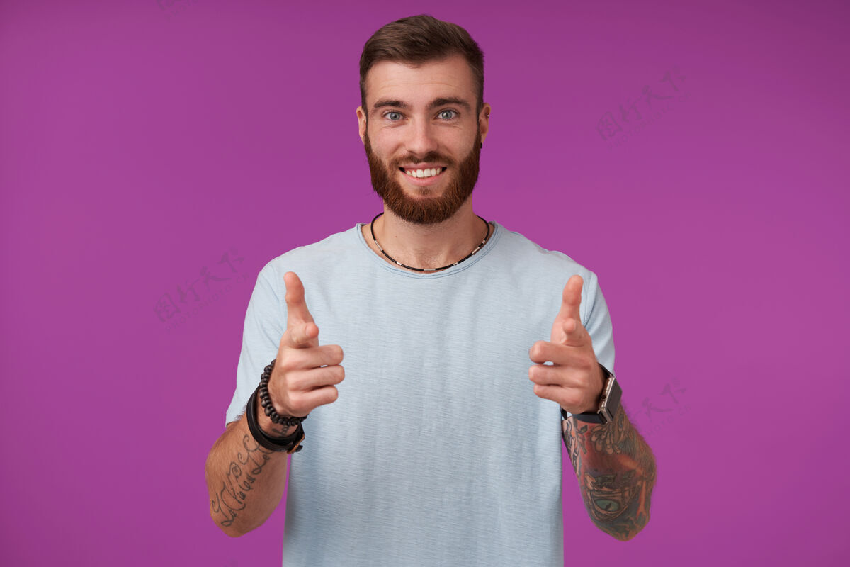 男人快乐的年轻迷人的黑发男人 胡须欢快地笑着 用大拇指举手 流露出愉快的情绪 孤立在紫色上肖像留胡子男人
