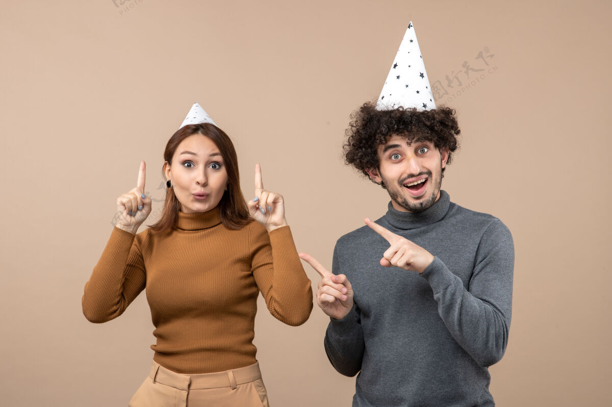夫妇新年概念与害怕年轻夫妇戴新年帽女孩和男孩灰色在一起年轻的夫妇男人