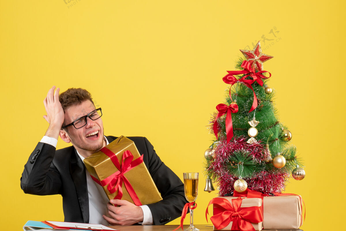 主管正面图：工作场所后面的男工人 黄色的桌子上摆着不同的礼物地点人男工人